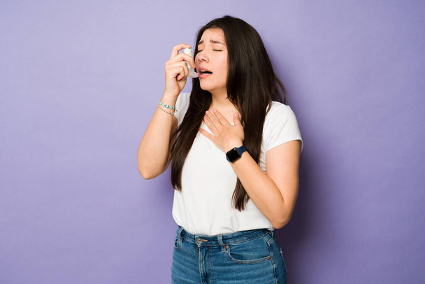 Astmaattinen sairas nuori nainen, joka käyttää inhalaattoria, kun hänellä on astmakohtaus tai hengitysvaikeuksia - Valokuva, kuva