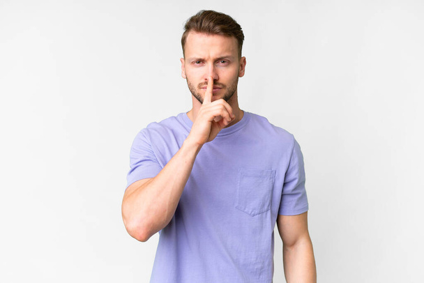 Young handsome caucasian man over isolated white background showing a sign of silence gesture putting finger in mouth - 写真・画像