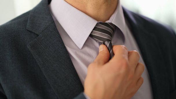 Businessman in suit straightening tie on shirt with hand closeup. Stylish elegant male look concept - Фото, изображение