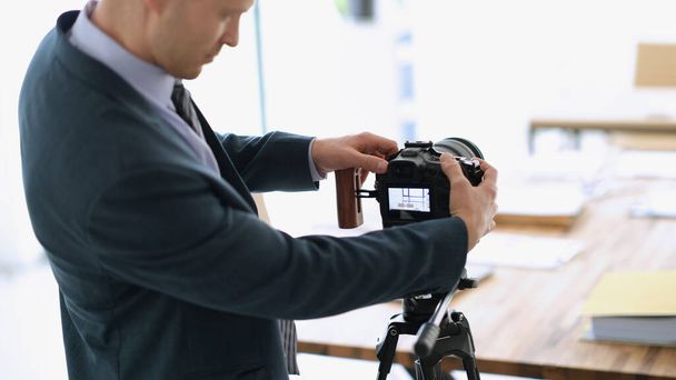 Empresario blogger ajustando la cámara a la audiencia para filmar la presentación. Concepto de webinars freelance y empresariales - Foto, Imagen