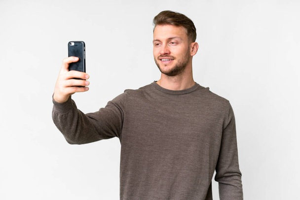 Young handsome caucasian man over isolated white background making a selfie - Foto, Imagem
