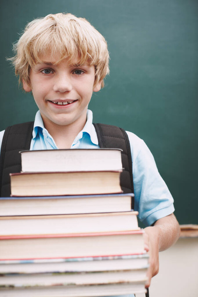 I can handle this. An eager young student carrying a tall stack of books and smiling at you - Foto, imagen