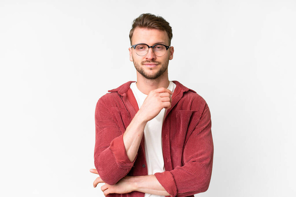 Jonge knappe blanke man over geïsoleerde witte achtergrond met bril en glimlach - Foto, afbeelding