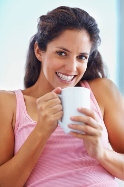 Beautiful woman holding a cup. Portrait of woman smiling and looking at you while holding a cup of coffee - Foto, immagini