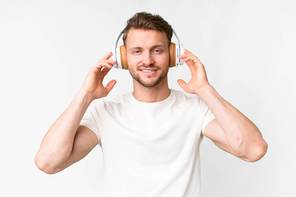 Young handsome caucasian man over isolated white background listening music - Foto, afbeelding