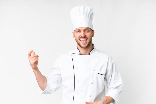 Young caucasian chef over isolated white background making guitar gesture - 写真・画像