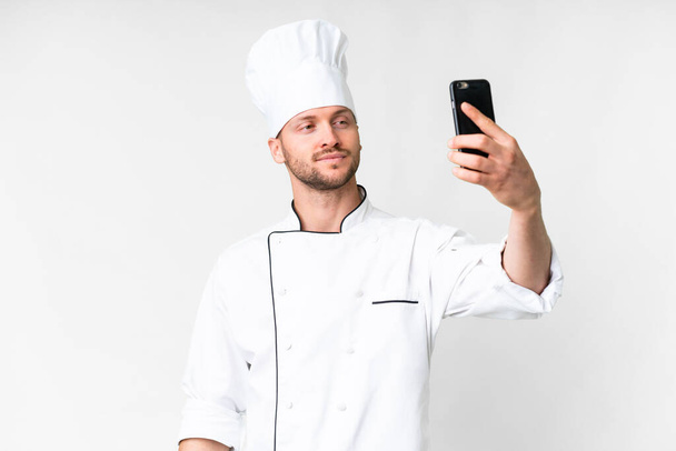 Young caucasian chef over isolated white background making a selfie - Фото, зображення