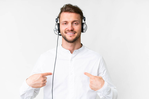 Telemarketer caucasian man working with a headset over isolated white background proud and self-satisfied - Fotó, kép
