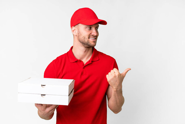 чоловік доставки піци з робочою формою збирання коробки для піци над ізольованим білим тлом, вказуючи на бік, щоб представити продукт
 - Фото, зображення