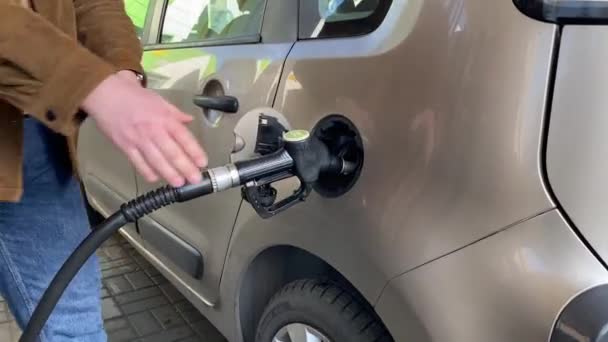 Ένας αγνώριστος επιχειρηματίας ανεφοδιάζει ένα αυτοκίνητο σε ένα βενζινάδικο. Ένας μεγαλύτερος άντρας ανεφοδιάζει το αμάξι του το ηλιοβασίλεμα. Καυκάσιος επιχειρηματίας γεμίζει πετρέλαιο και καύσιμα στο αυτοκίνητο στο βενζινάδικο Η έννοια των τιμών της βενζίνης - Πλάνα, βίντεο