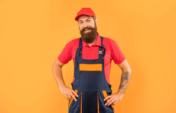happy bearded deliveryman in work clothes on yellow background. - Foto, immagini