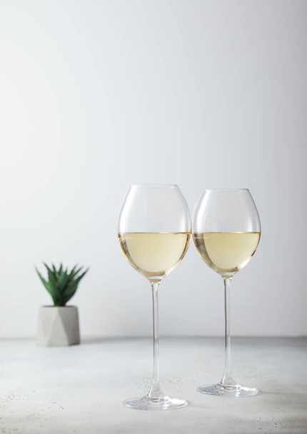 Gläser Weißwein und kleine grüne Blume auf heller Tafel. - Foto, Bild