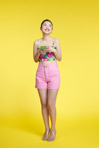 young woman wearing  tank top, holds mobile phone in hands and rejoices positive news - Photo, image
