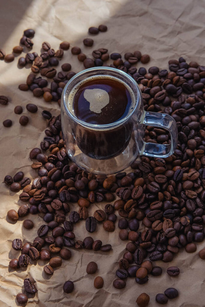 Kahvipapuja ja kuppi kahvia ruskealla paperilla tausta - Valokuva, kuva