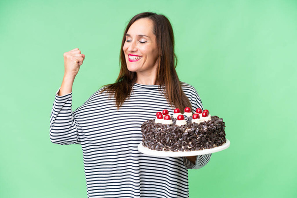 Middle age caucasian woman holding birthday cake over isolated chroma key background celebrating a victory - Zdjęcie, obraz