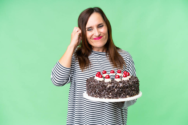 Middle age caucasian woman holding birthday cake over isolated chroma key background frustrated and covering ears - Foto, imagen