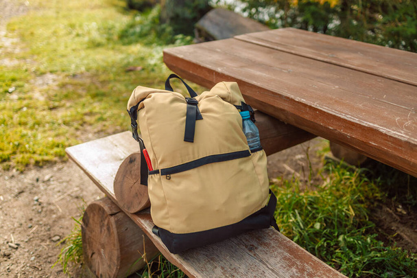 A closeup of a backpack and a water bottle on a bench in the mountain park. High quality photo - Fotoğraf, Görsel