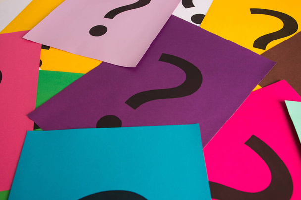 Black question marks on the colored papers, top view - Фото, изображение