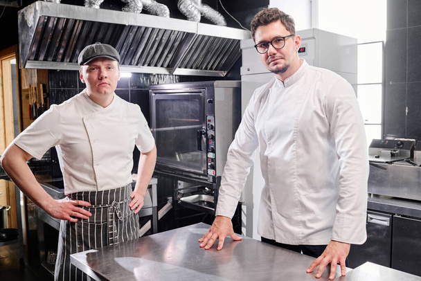 Portrait of confident chef and cook looking at camera while working in commercial kitchen - Photo, Image