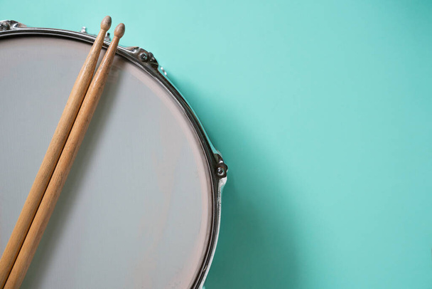 Drum stick and drum on green table background, top view, music concept - Фото, зображення