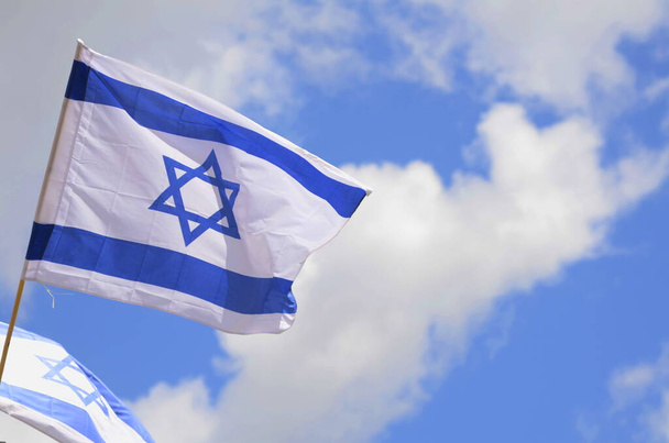 Flag of Israel against a bright blue sky. Star of David on a white background. - Foto, imagen