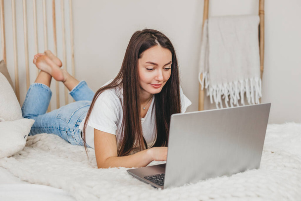 Közelkép egy lányról, aki otthon dolgozik egy laptopon, és a képernyőt nézi. Fiatal női szövegíró, távoli munka, szabadúszó koncepció - Fotó, kép