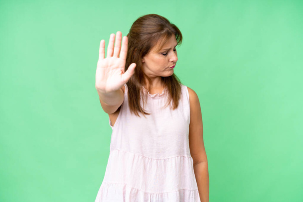 Frau mittleren Alters über isolierten Hintergrund macht Stop-Geste und enttäuscht - Foto, Bild