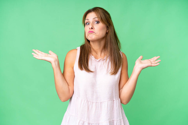 Middle age woman over isolated background making doubts gesture - Foto, imagen