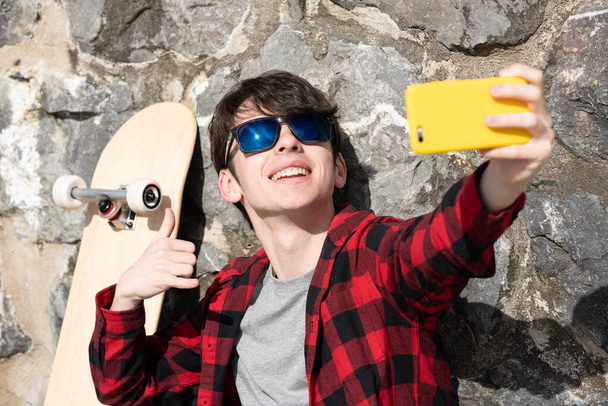 Cool teenager boy taking selfie outdoors - 写真・画像