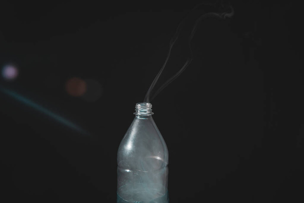 Moving smoke coming out of a plastic bottle. Isolated on black background. - Photo, Image