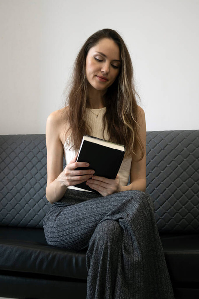 Slim woman sits and reads a paper book. The Benefits of Reading. How Reading Can Improve Your Life - 写真・画像