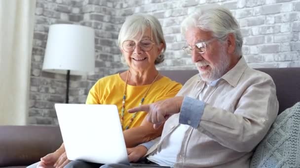 riprese di una bella coppia romantica di anziani che utilizzano il computer portatile insieme sul divano di casa - Filmati, video