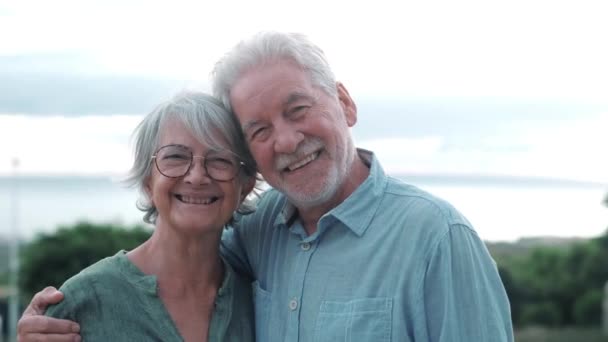 imágenes de dos jubilados o pensionistas felices y activos divirtiéndose y disfrutando mirando el atardecer sonriendo con el mar - ancianos al aire libre disfrutando de vacaciones juntos - Imágenes, Vídeo