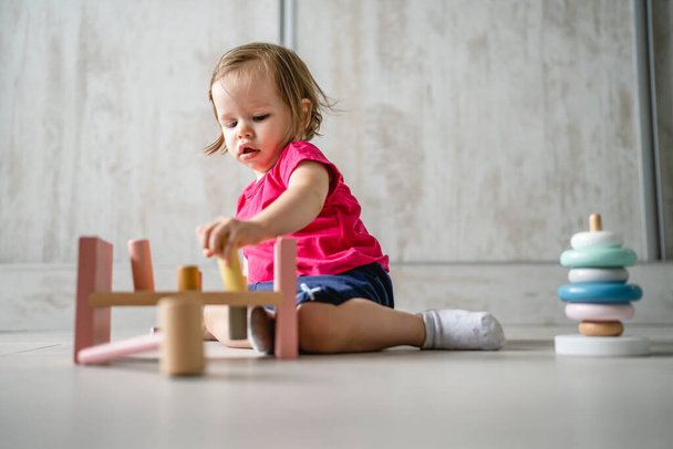 ένα παιδί μικρό καυκάσιο κορίτσι μικρό παιδί παίζει με εκπαιδευτικά παιχνίδια στο σπίτι παιδική ηλικία και μεγαλώνοντας νωρίς ανάπτυξη έννοια αντιγραφή χώρο μπροστά άποψη - Φωτογραφία, εικόνα