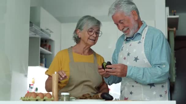 πλάνα από όμορφο ζευγάρι ηλικιωμένων μαγείρεμα μαζί στην κουζίνα - Πλάνα, βίντεο