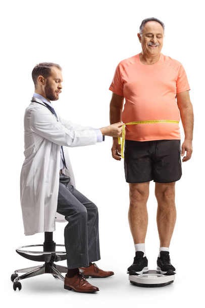 Doctor measuring a mature man in a sportswear isolated on white background - Foto, afbeelding