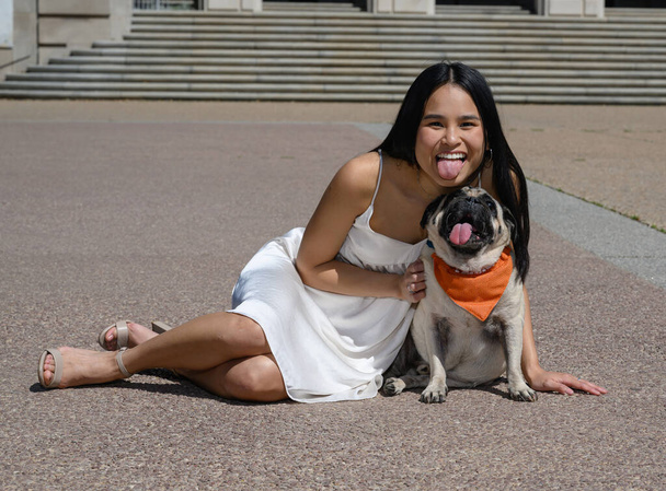 Jeune fille américaine asiatique attrayante avec son chien de carlin se préparant pour l'obtention du diplôme universitaire  - Photo, image