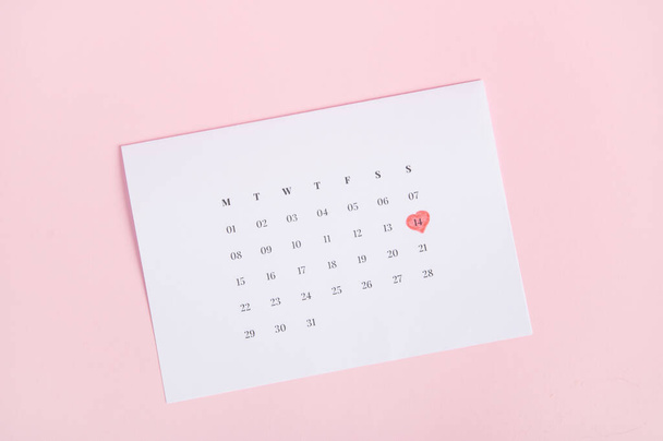 Still life with a white calendar marked with the date February 14 - Valentines Day, isolated over pink pastel background. Falt lay - Photo, Image