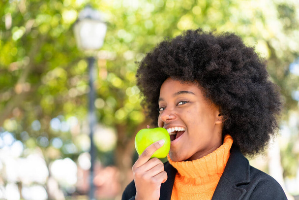 Afroamerykanka na zewnątrz trzyma jabłko - Zdjęcie, obraz