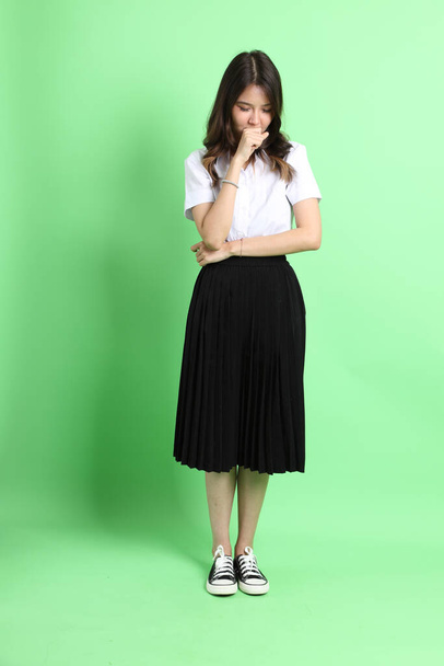 The young school girl with uniform standing on the green background. - 写真・画像
