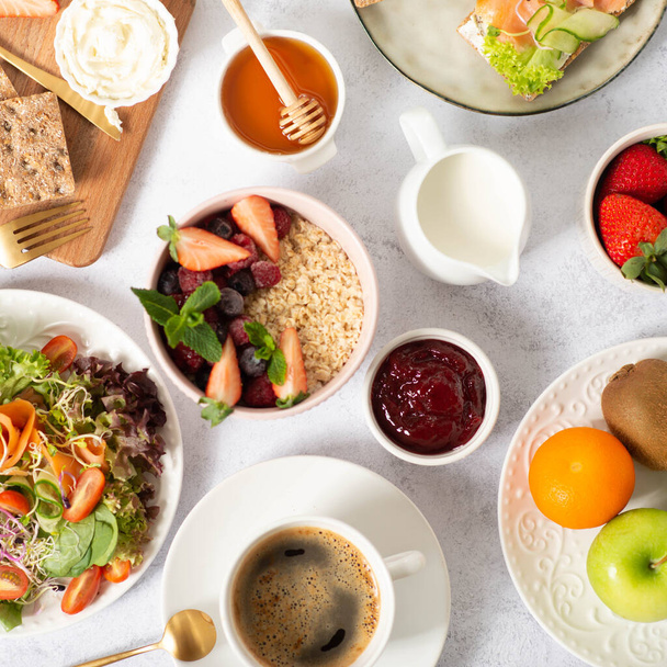 Gesundes Frühstück auf grauem Hintergrund. Das Konzept der leckeren und gesunden Ernährung. Draufsicht, Kopierraum. gesundes Frühstück. Obst, Salat, Haferflocken mit Erdbeeren. Ernährung - Foto, Bild