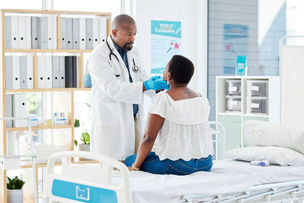 Appointment, medical and doctor consulting a patient checking her neck in a hospital bed or clinic for health. Black man, consultation and healthcare professional examine a woman with injury or sick. - Photo, image