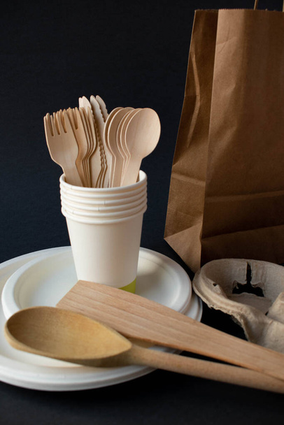 Kraft paper tableware on dark background. Paper cups and containers, wooden cutlery. Paper packaging for street food, recyclable paper tableware, waste-free packaging concept. Layout, flat layout - Photo, Image