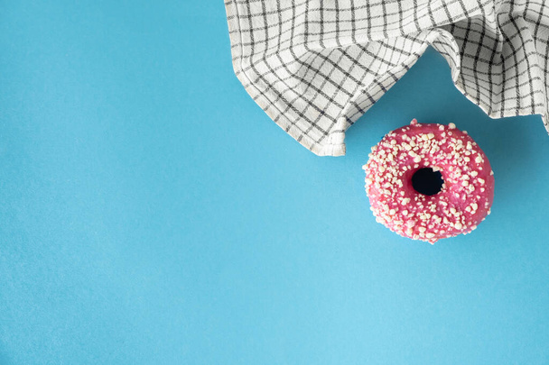 Top kilátás fánk rózsaszín csokoládé cukormáz a kék pasztell háttér. Reggeli koncepció. Étel mockup másolási hellyel az ingyenes szöveghez. Lapos fekvés. Rózsaszín mázzal bevont fánk - Fotó, kép