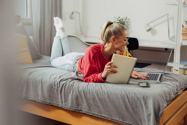 A cute caucasian woman is studying on the bed - Photo, image