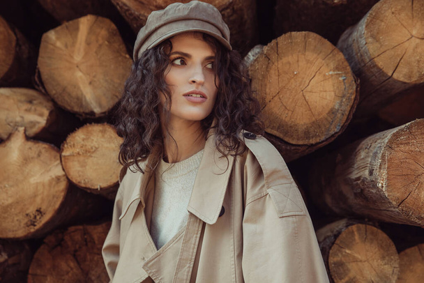Young beautiful girl, brunette with curly hair. Dressed in a stylish beige trench coat and cap. - Zdjęcie, obraz