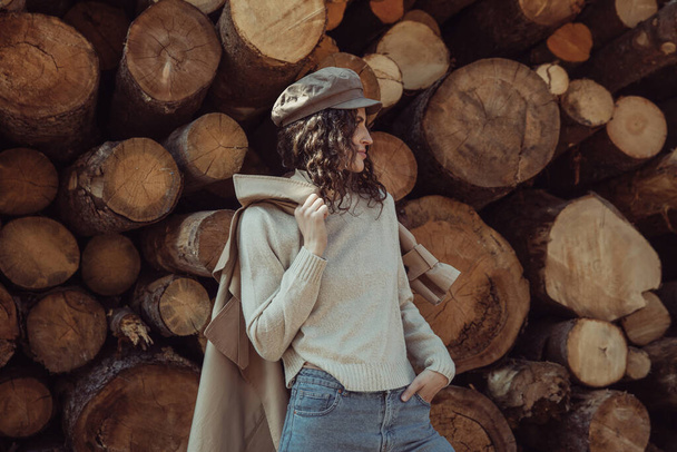 Young beautiful girl, brunette with curly hair. Dressed in a stylish beige trench coat and cap. - Foto, Bild