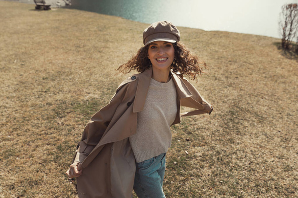 Happy young woman with curly hair in trendy look. Spring or warm autumn weather. - Foto, imagen