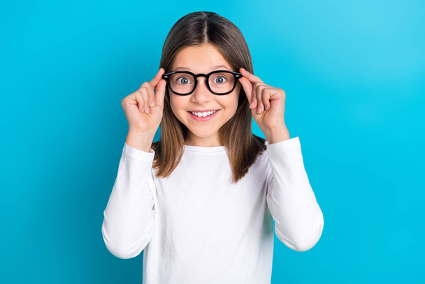 Photo of impressed girl with long hairstyle wear white long sleeve fingers touch glasses staring isolated on blue color background. - Foto, Bild