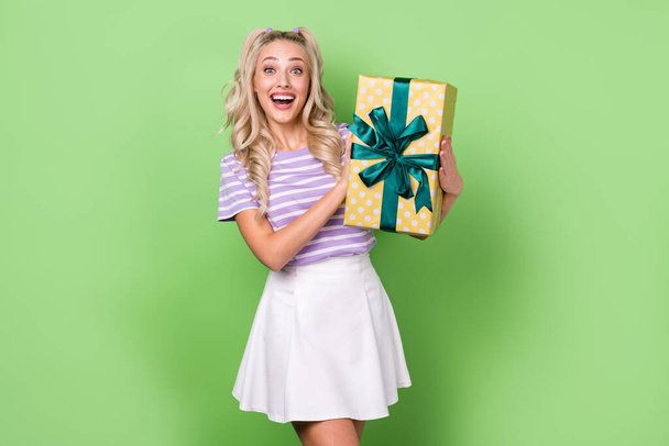 Portrait of positive cheerful lovely woman wavy hairstyle tabby t-shirt impressed present on birthday isolated on green color background. - Foto, Imagem